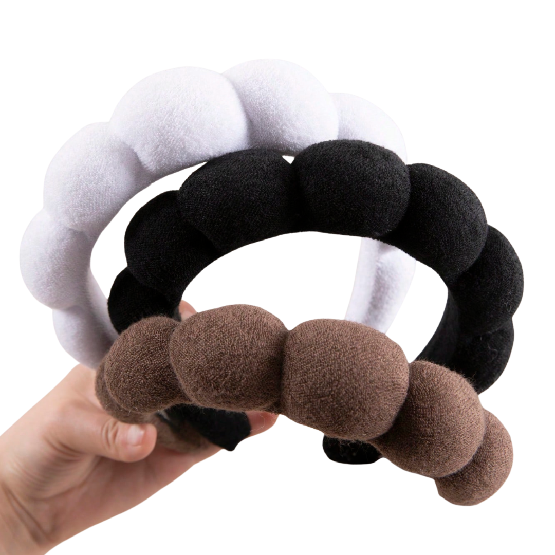 Set of three textured hair ties in gray, black, and brown held by a hand on a white background self tanning bundle.