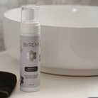 Byremi tanning moisturizer bottle on a bathroom counter with a blurred background